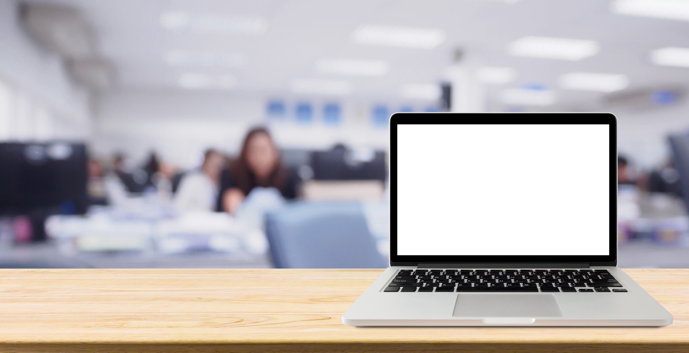 Laptop with blank screen on desk table with blur office interior background